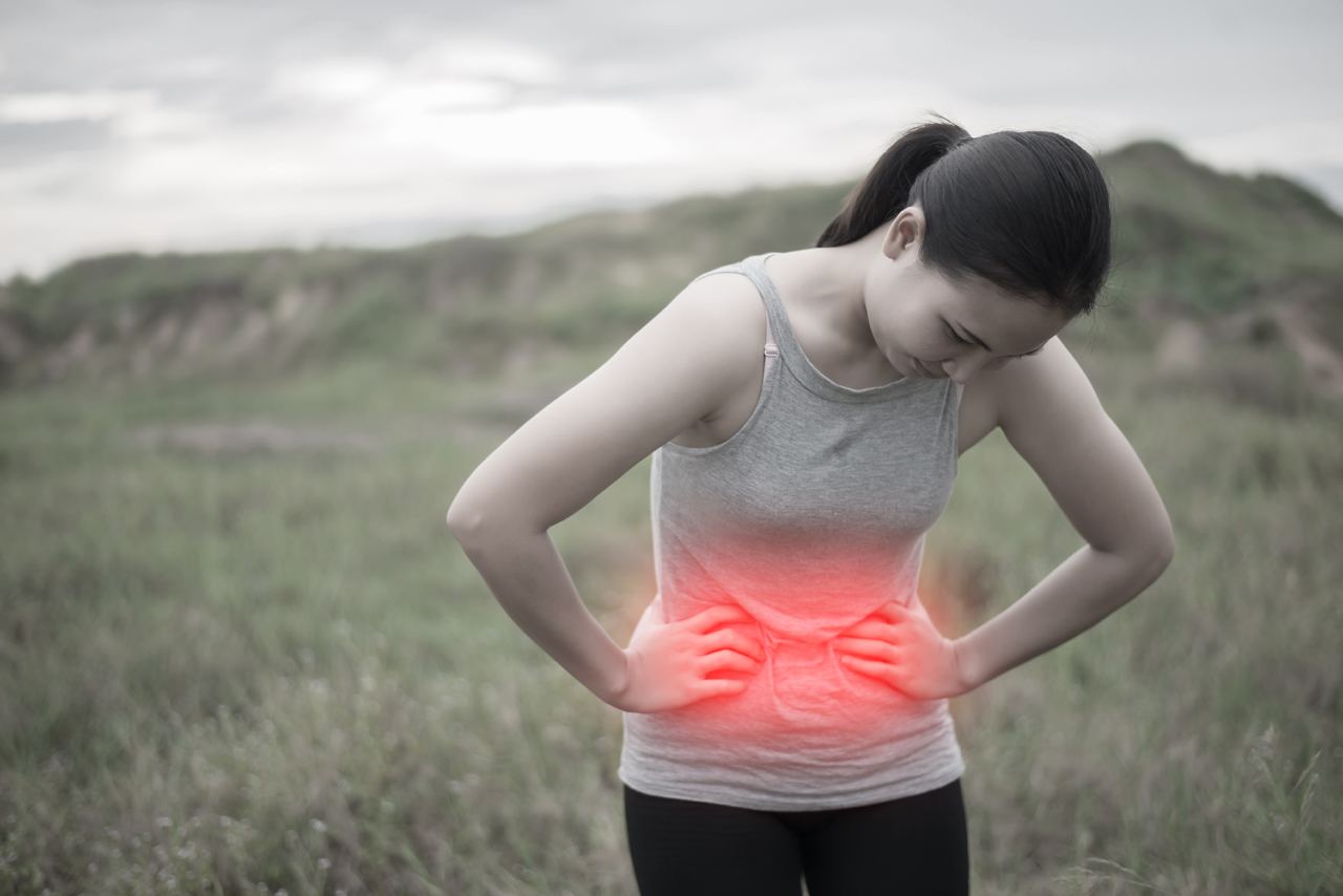 A woman bent at the hips with illustration indicating she is in stomach pain